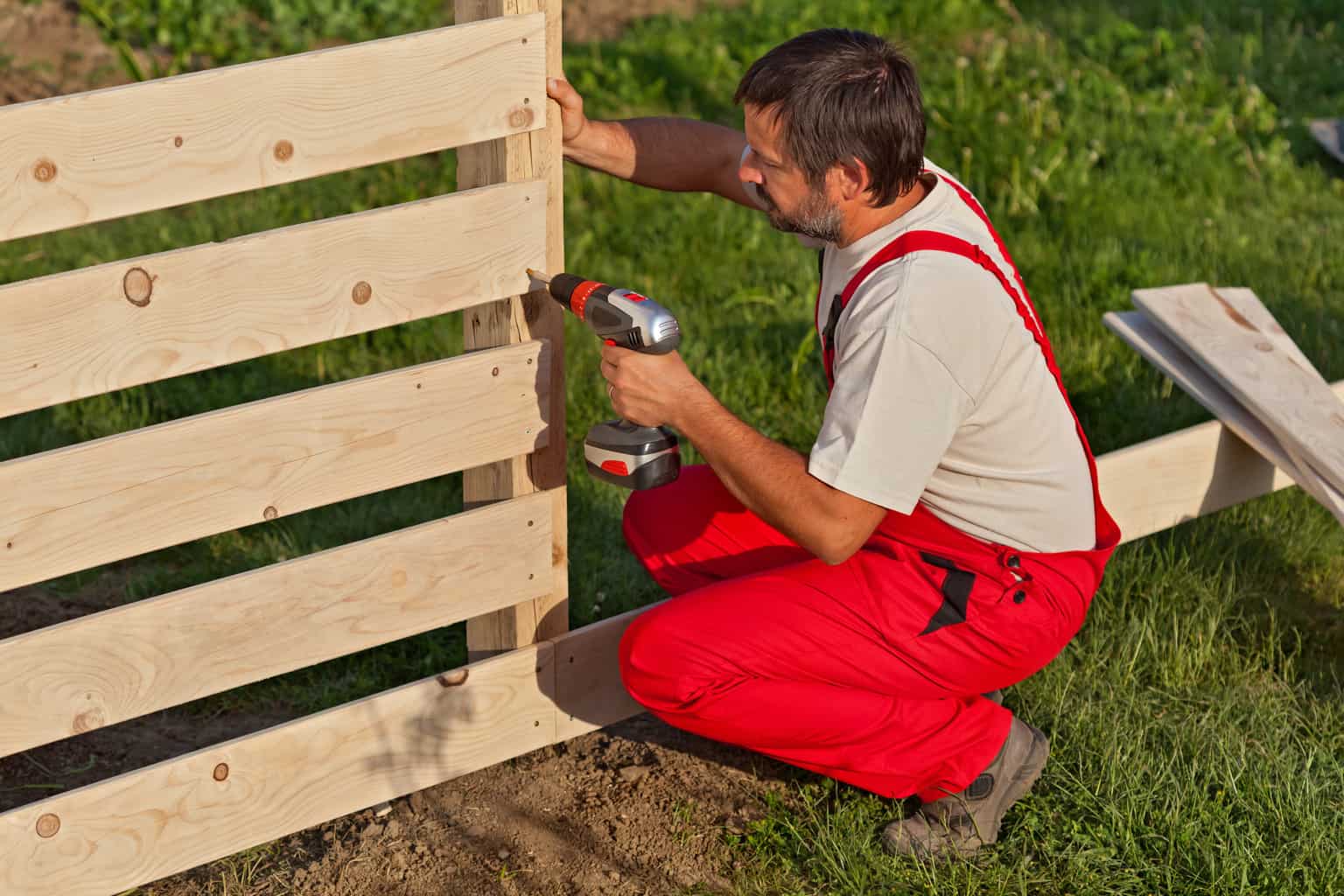 Friendly Earth Fence Contractors Calgary installing a custom wooden fence.